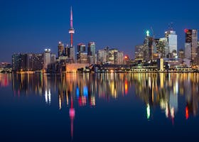 Stunning night view of Toronto skyline reflecting on water with CN Tower prominent.